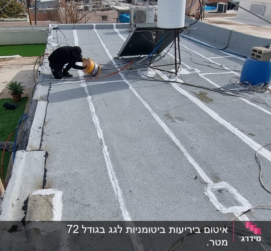 אדם מורח חומר איטום על גג שטוח